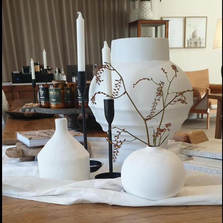 Decorative vases on a wooden table in a room with furniture and decor.